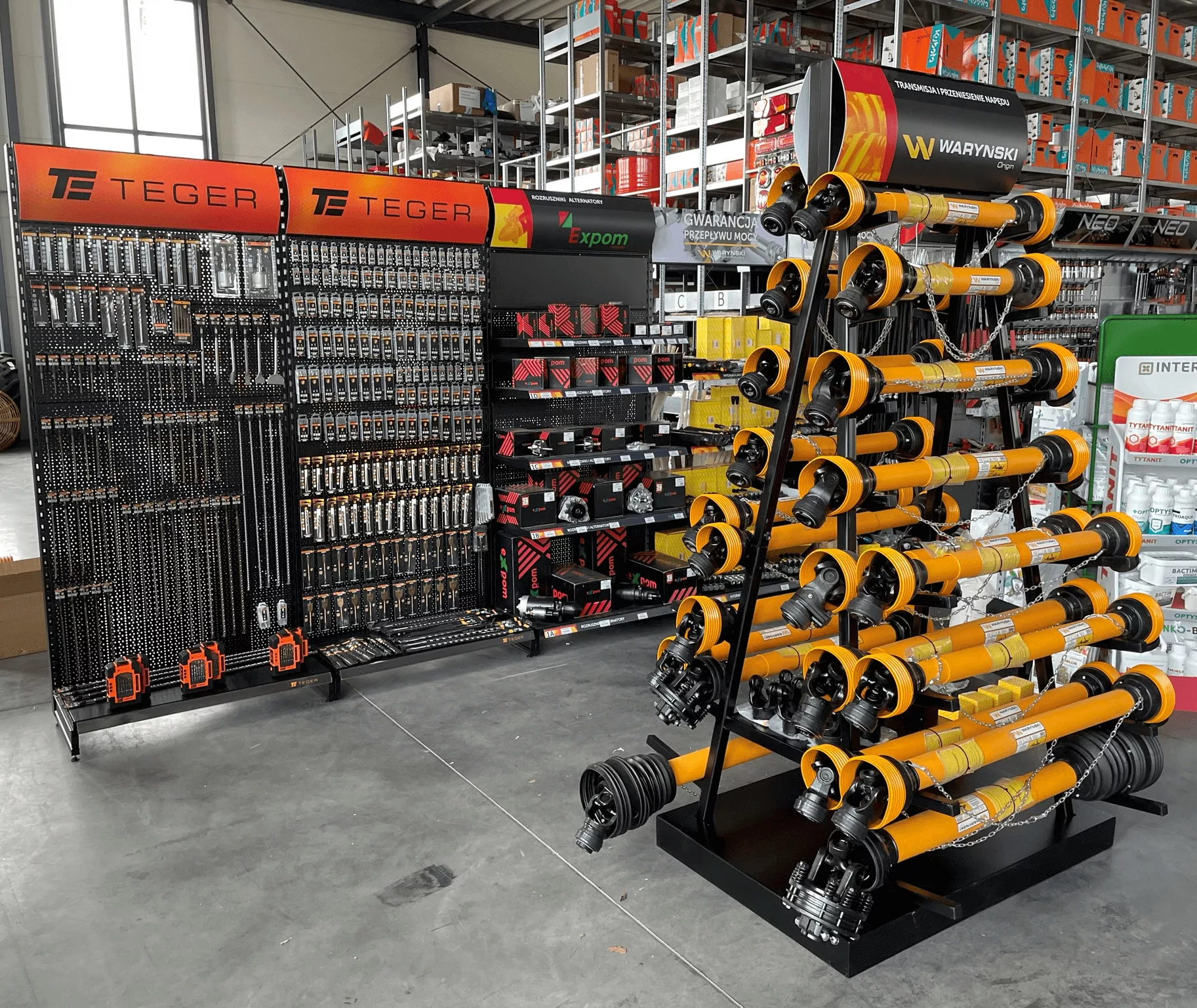 Warehouse of brake parts with calipers, drums and wheel parts arranged on a black-red counter, with rows of parts boxes on the walls