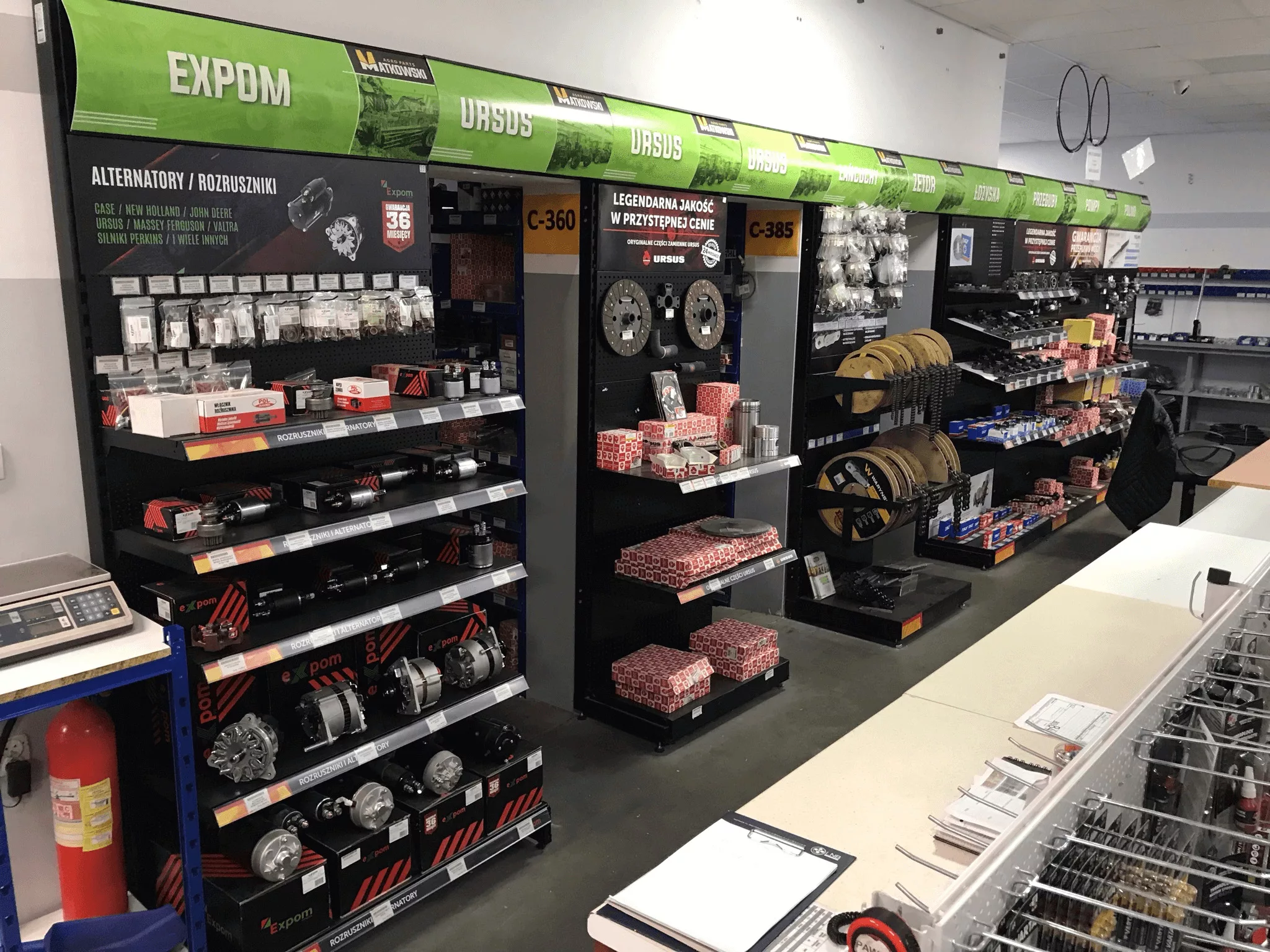 Shop layout visualization with black shelves, wooden pallets and yellow wall accents. The project shows a retail space with systematically arranged equipment elements, Rolmar logo in the bottom right corner